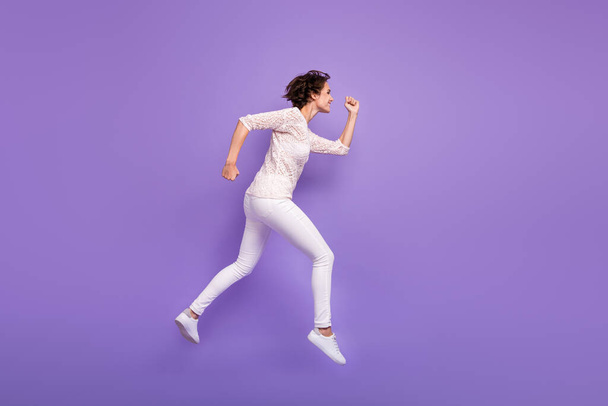 Full length photo of charming purposeful young lady dressed white shirt jumping running isolated purple color background - 写真・画像