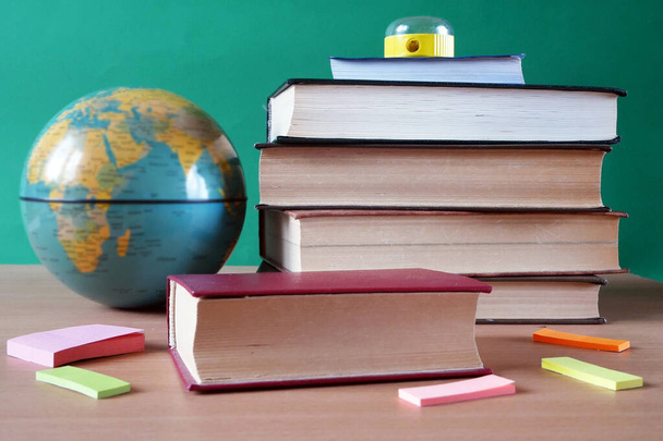Terug naar school, boeken stapel, potloden, wereldbol over schoolbord achtergrond, close-up - Foto, afbeelding