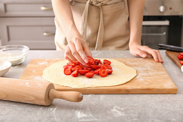 Femme préparant la galette de fraises sur la table dans la cuisine - Photo, image