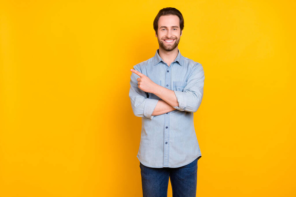 Φωτογραφία του νεαρού χαρούμενου άνδρα ευτυχής θετικό χαμόγελο δείχνουν δάχτυλο κενό χώρο επιλέξτε προτείνει απομονωμένη πάνω από κίτρινο χρώμα φόντο - Φωτογραφία, εικόνα