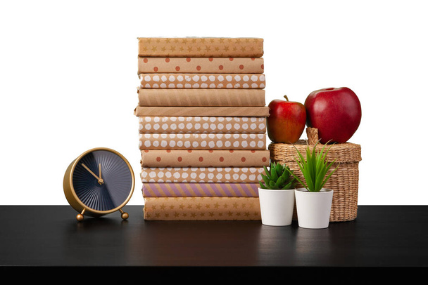 Stapel Bücher und Apfel auf Tischplatte vor weißem Hintergrund - Foto, Bild