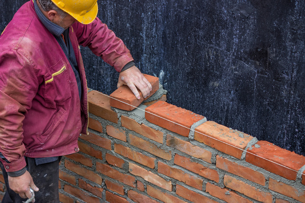 Constructor trabajador que pone ladrillo de arcilla sólida
 - Foto, imagen