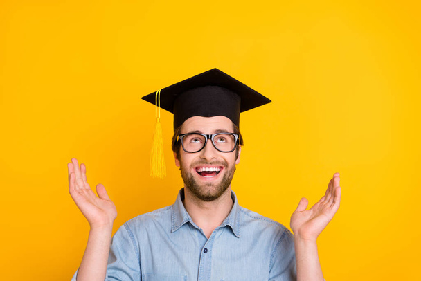 Photo of young man happy positive smile amazed excited look empty space mortarboard isolated over yellow color background - Φωτογραφία, εικόνα