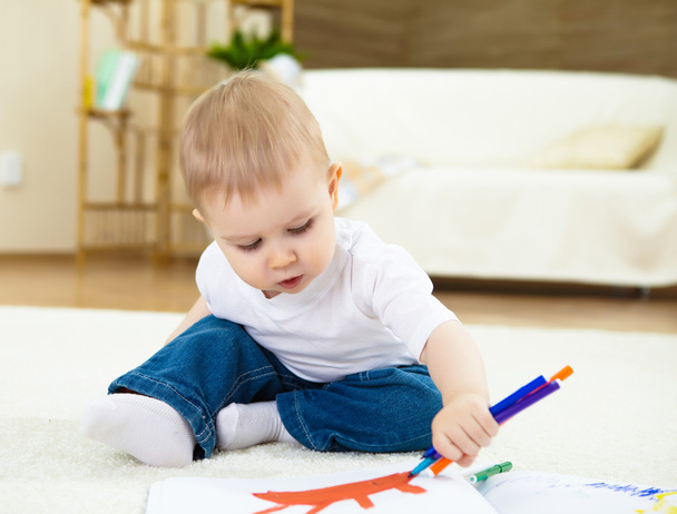 Little boy drawing with color pencil and sitting on the floor at home - Fotó, kép