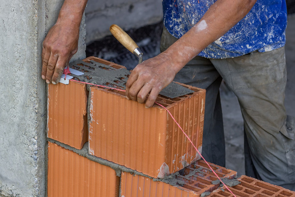 robotnik budowlany ustawienie ciąg linii między gliny bloku - Zdjęcie, obraz