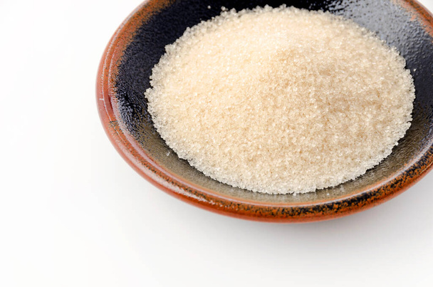 San-ontou, Light brown sugar in a black plate on white background - Photo, Image