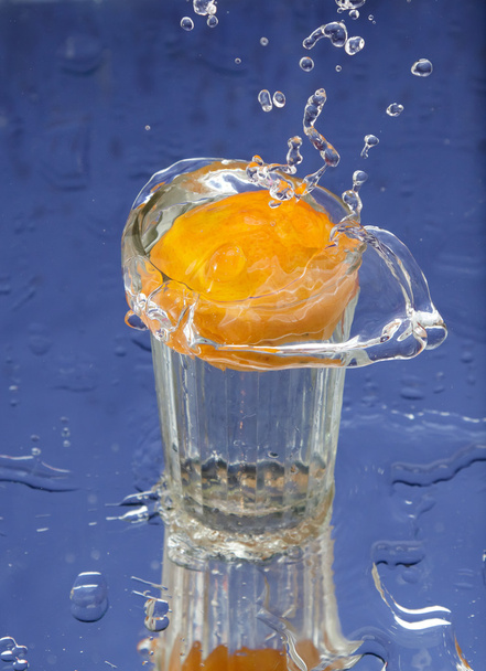 Orange and splash water over blue background - Foto, afbeelding
