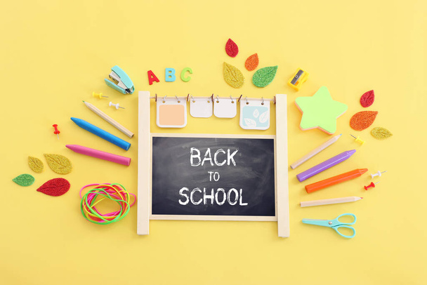 Back to school concept. Top view image of blackboard and student stationery over pastel yellow background - Foto, afbeelding