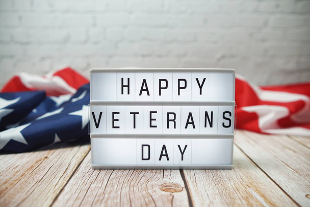 Happy Veterans Day word in lightbox and American flag on wooden background - Foto, afbeelding