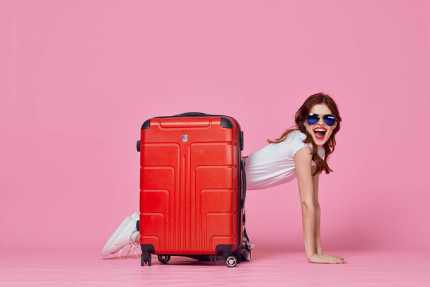 женщина туристка с красным чемоданом на розовом фоне. Высокое качество фото - Фото, изображение