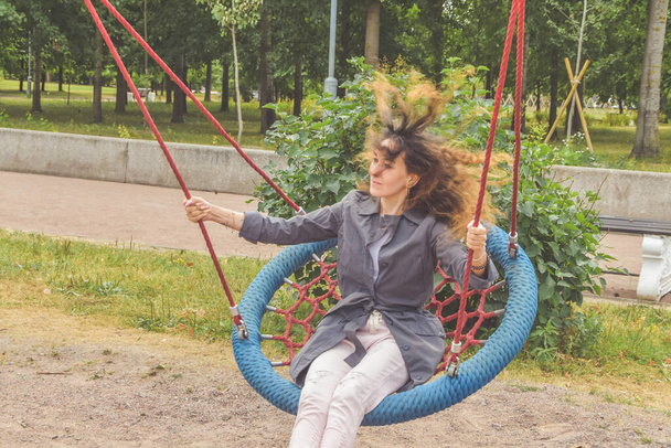 a girl swings on a swing in the park on a sunny day - Foto, afbeelding