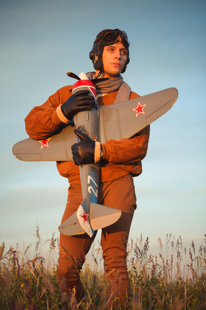 Хлопець в старовинному одязі пілот з моделлю літака на відкритому повітрі
 - Фото, зображення