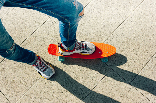 Giovane in jeans strappati in piedi con penny board nel parco. attività estive skateboard - Foto, immagini