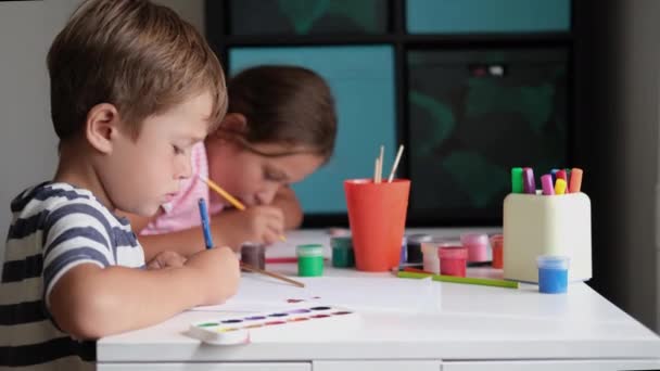4k. μικρό χαριτωμένο καυκάσιο κορίτσι και αγόρι ζωγραφίζει μαζί στο σπίτι - Πλάνα, βίντεο