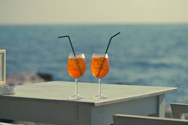Dois coquetéis laranja com palhinhas na mesa junto à praia, conceito de férias - Foto, Imagem