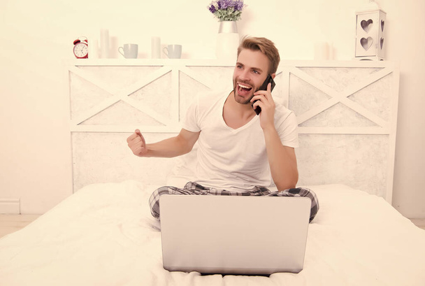 Happy guy make winner gesture talking on mobile phone in bed, victory - Фото, изображение