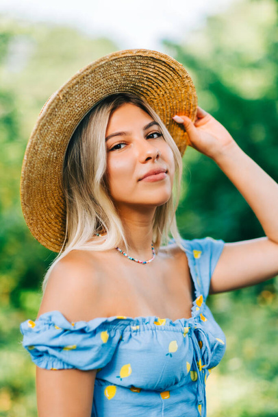 Portrait of attractive young woman in straw hat outdoors in summer sunny day. - Foto, Imagem