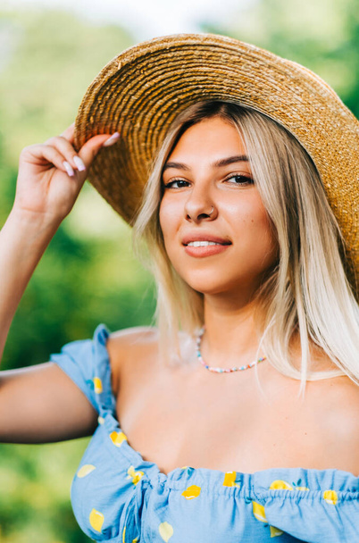 Portrait of attractive young woman in straw hat outdoors in summer sunny day. - Foto, immagini