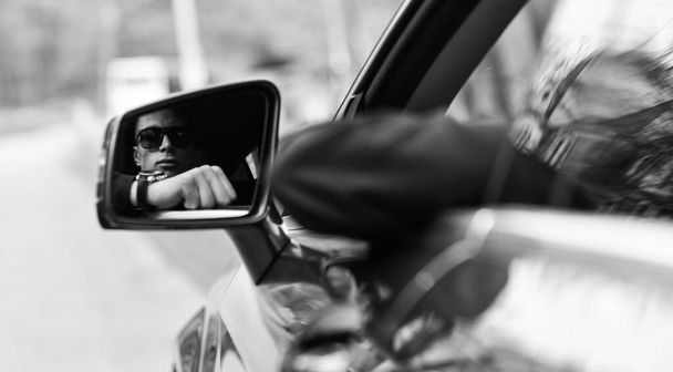 New point of view. Guy drive automobile. Driver seen in car mirror. Side or rear view mirror. Mirror reflection of handsome man. Transport and transportation. Vacation trip. Adventure and discovery - Фото, изображение