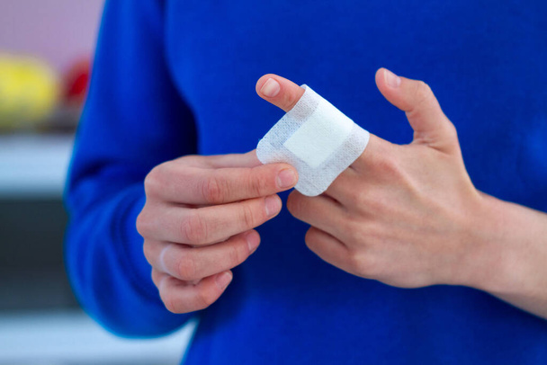 Woman using adhesive plaster for injured finger. First aid for cuts and wounds - Foto, immagini