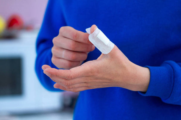 Woman using a medical sticking plaster for injured finger. First band aid for cuts and wounds - Foto, afbeelding