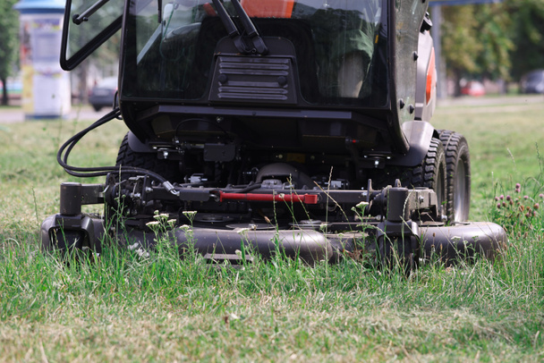 トラクター芝生芝刈り機公園近くの草を刈る - 写真・画像