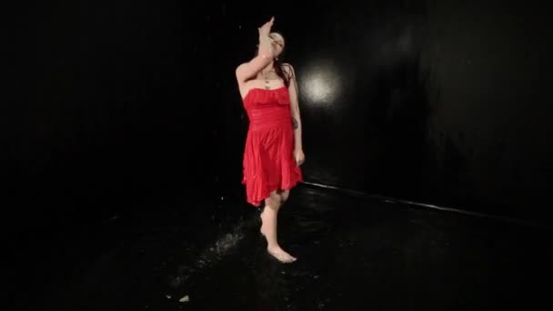 Γυναίκα με κόκκινο φόρεμα στροβιλίζεται ενώ χορεύει ενώ στέκεται στο νερό. - Πλάνα, βίντεο