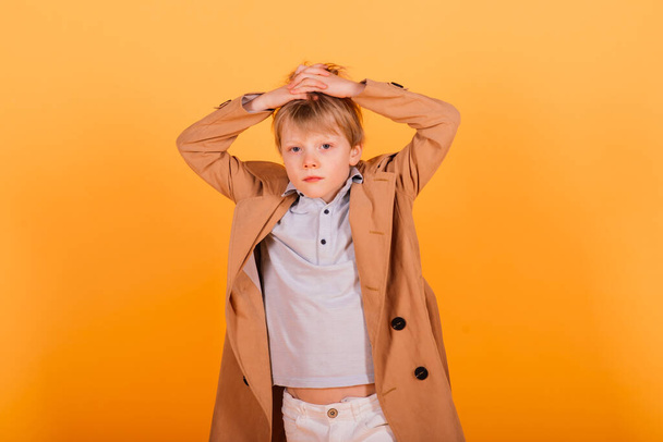 Grimacing emotional redhead fasion boy posing in a yellow studio - Photo, Image