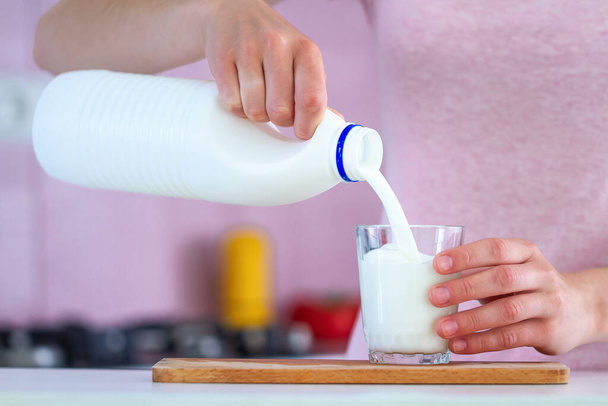 Female is pouring fresh milk into a glass close up. Dairy products - Foto, imagen