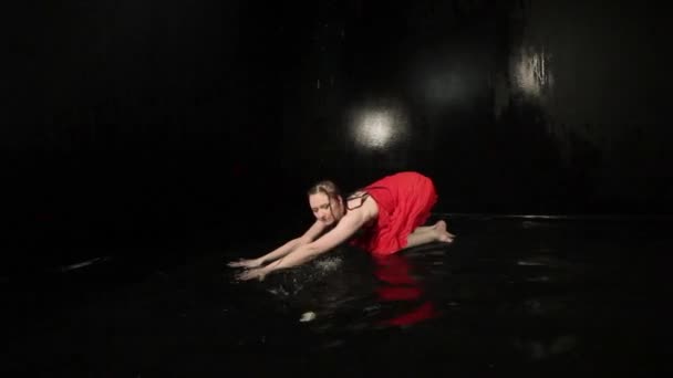 Mujer con un vestido rojo gira mientras baila mientras está de pie en el agua. - Metraje, vídeo