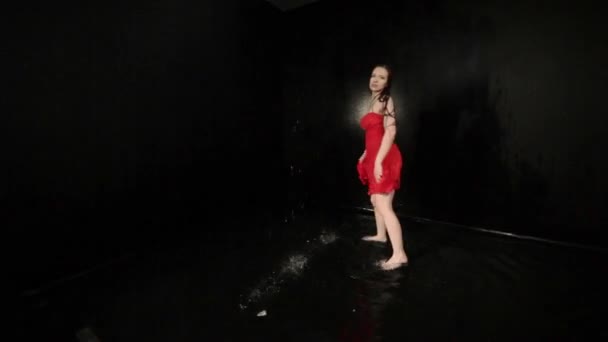 vrouw in een rode jurk wervelt terwijl dansen terwijl staan in het water. - Video