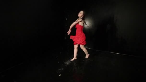 Mujer con un vestido rojo gira mientras baila mientras está de pie en el agua. - Imágenes, Vídeo