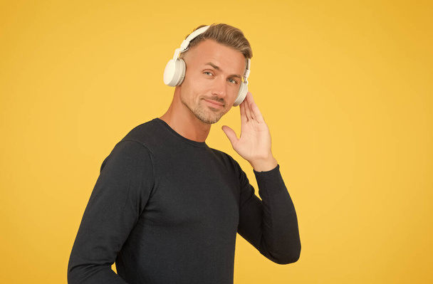 smiling stylish mature guy with trendy hairstyle wearing earphones listening ebook or audio book for study online, digital technology - Zdjęcie, obraz