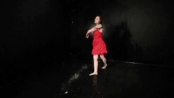 Kobieta w czerwonej sukience wiruje podczas tańca stojąc w wodzie. - Materiał filmowy, wideo