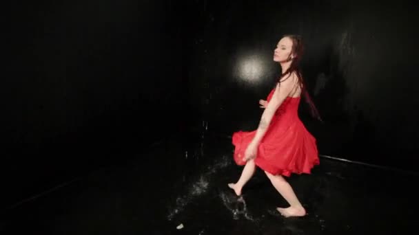 Donna in un abito rosso vortici mentre balla mentre in piedi in acqua. - Filmati, video