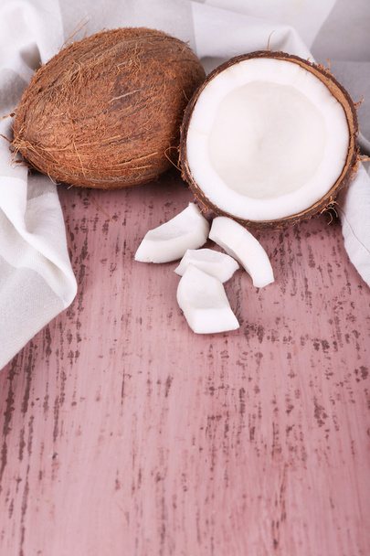 Broken coconut with napkin on wooden background - Фото, изображение