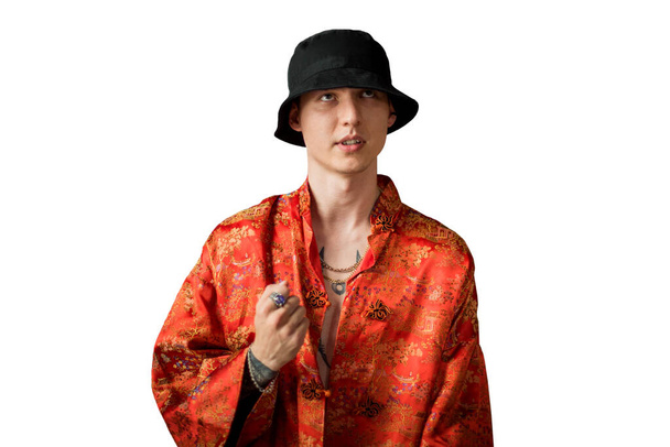 Positives Männerporträt mit rotem Kimono im Streetstyle und Ketten um den Hals. Jugend- und Lebensstilkonzept. Luxus-Rapkünstler. Isoliert auf Weiß. - Foto, Bild
