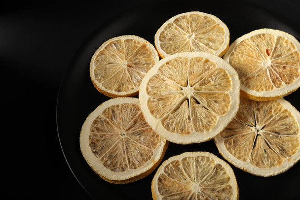 Сушені скибочки лимона в чорній тарілці
 - Фото, зображення