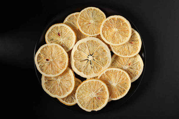Rodajas de limón secas en un plato negro - Foto, imagen