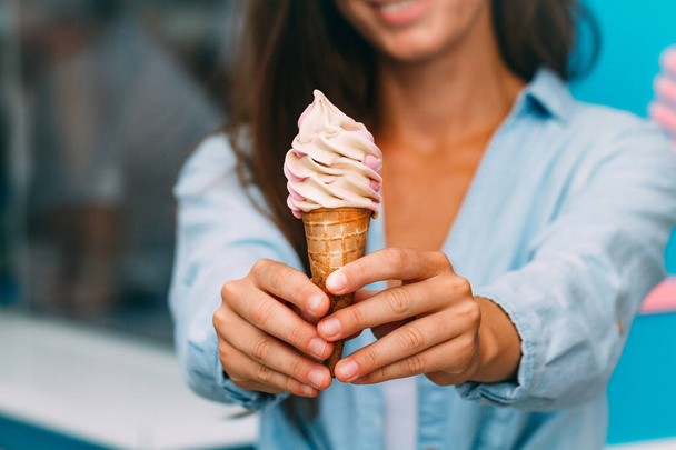 Smiling woman enjoys her sweet ice cream during a summer day near ice cream truck  - Fotó, kép