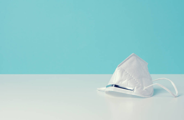 bílá jednorázová lékařská maska na modrém pozadí, osobní ochranné prostředky pro dýchací cesty před virovými infekcemi, kopírovací prostor - Fotografie, Obrázek