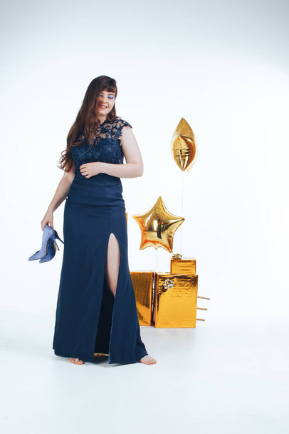 Woman dancing wearing night party dress on white background with golden inflatable star and gift boxes. Party corporate event times in epidemic, christmas and birthday concept - 写真・画像