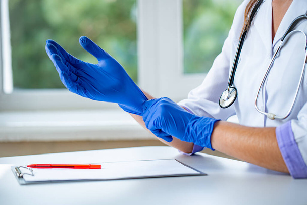 Doctor puts on blue rubber medical gloves for medical examination of a patient in a clinic. Health care  - Zdjęcie, obraz