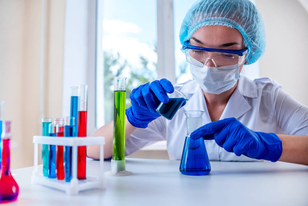 Female laboratory assistant using various scientific glassware and test tubes for clinical laboratory researches and tests. Medicine, pharmacy and cosmetology concept.  - Photo, image
