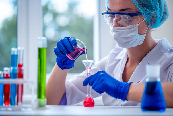 Female chemist using scientific glassware and test tubes for clinical laboratory researches, analysis and tests. Medicine, pharmacy and cosmetology concept.  - Фото, зображення