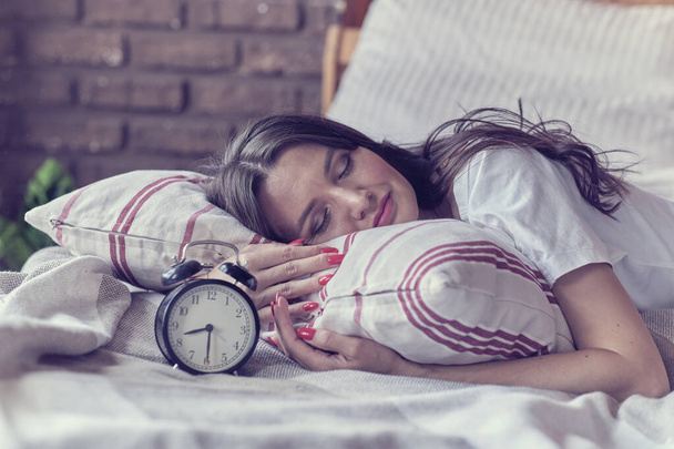 μεσήλικη γυναίκα κοιμάται και ξυπνητήρι στο υπνοδωμάτιο στο σπίτι. έννοια του χρόνου ύπνου - Φωτογραφία, εικόνα