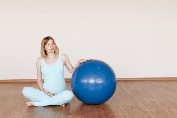a pregnant woman with a fitness ball in the studio. motherhood - Фото, зображення