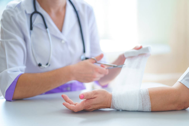 Doctor is bandaging wrist of patient in clinic  - Fotoğraf, Görsel