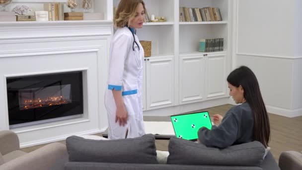 Γυναίκα γιατρός εξηγεί στον ασθενή τα αποτελέσματα των ιατρικών εξετάσεων σε φορητό υπολογιστή κατά τη διάρκεια της επίσκεψης homecare - Πλάνα, βίντεο