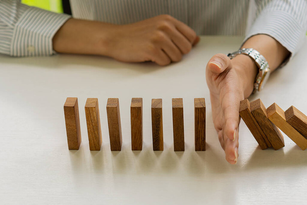 Businessman Stop falling wooden block domino from continuous falling or risk to construction business and strategy. Successful idea. - Photo, Image